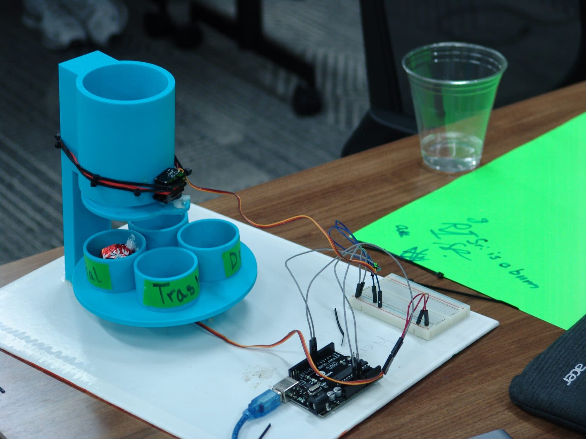 A 3D-printed smart trash-sorting prototype wired to an Arduino on a team's table