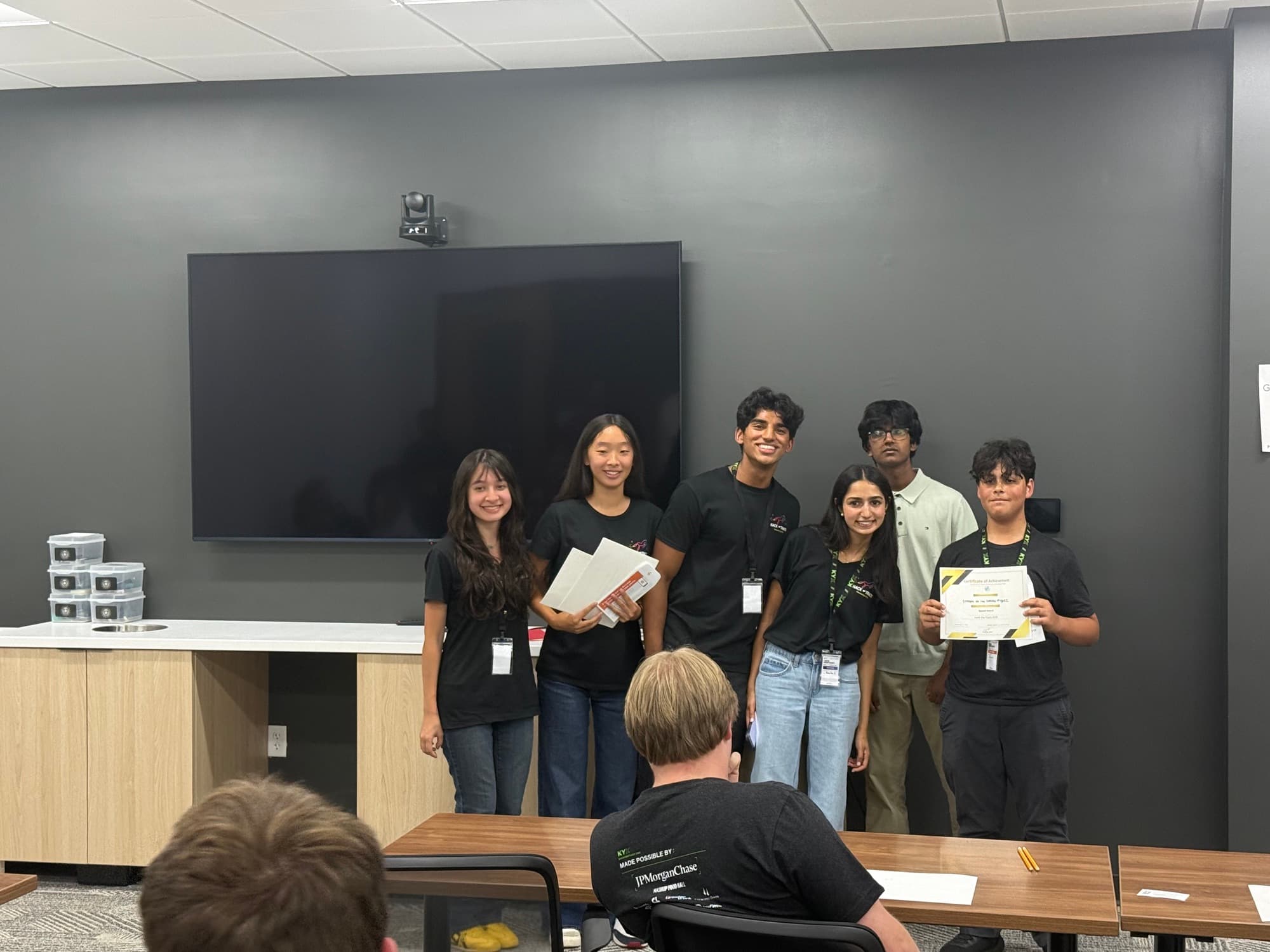 An award winner holding their certificate with the Hack the Track organizing team at the 2026 awards ceremony