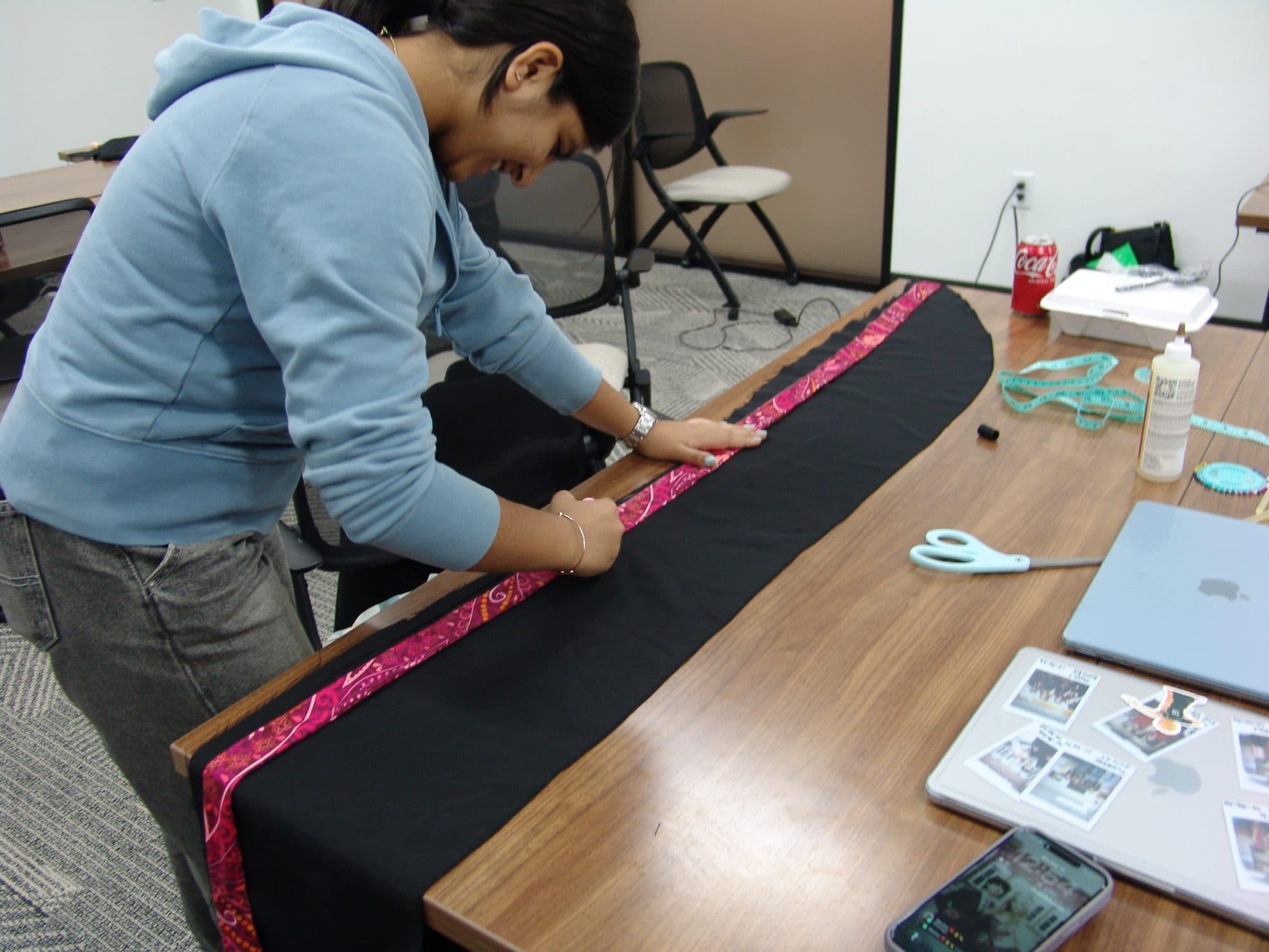 A student pinning pink trim onto black fabric for a sustainable fashion track project