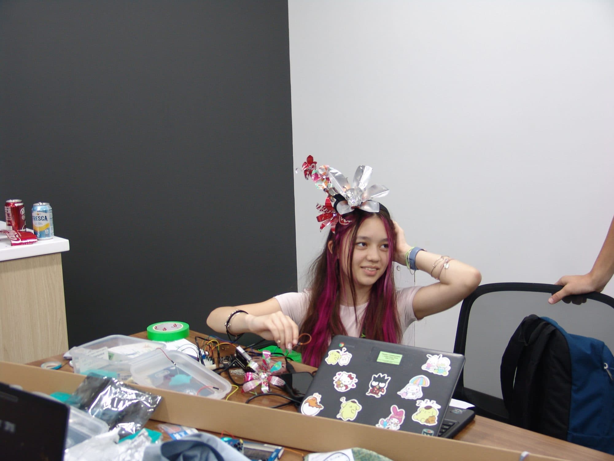 A student smiling while trying on a wearable prototype made from recycled materials